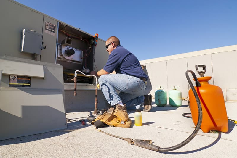 hvac technician making commercial hvac repairs on a roof