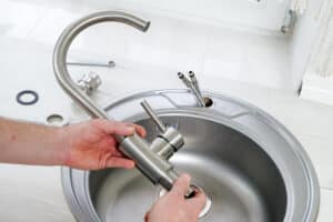 Close up of a plumber holding a new sink faucet to be installed